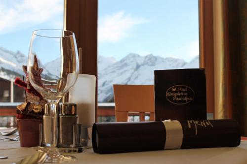 a table with a wine glass and a bottle of wine at Hotel Königsleiten Vital Alpin in Königsleiten