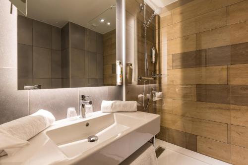 uma casa de banho com um lavatório branco e um espelho. em ibis Styles Geneve Palexpo Aeroport em Genebra