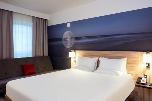 a hotel room with a large bed and a large window at Novotel London Stansted Airport in Stansted Mountfitchet