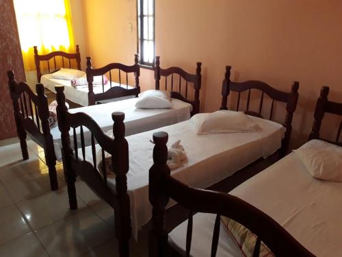 a group of four beds in a room at Pousada Casa D` Guio in Rio das Ostras