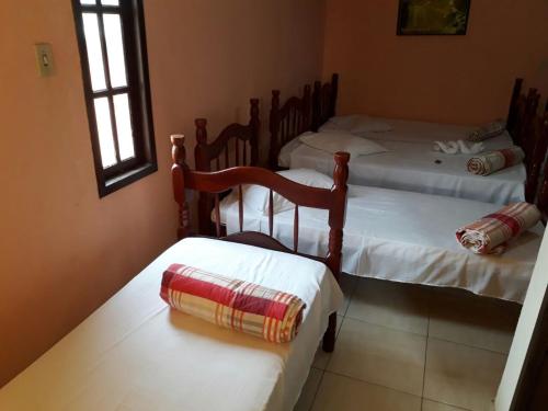 two twin beds in a room with two windows at Pousada Casa D` Guio in Rio das Ostras