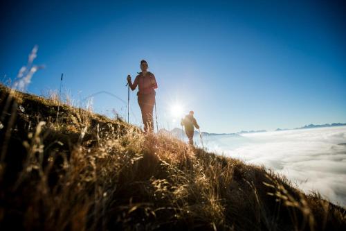 two people standing on top of a hill with the sun behind them at XL Appartements Sand in Taufers in Campo Tures