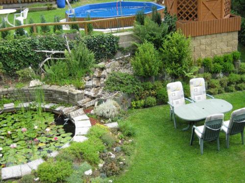 a garden with a table and chairs and a pond at Penzion Gerta in Český Krumlov