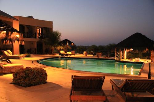 a swimming pool with two chairs and a building at Pousada Aruana in Canoa Quebrada