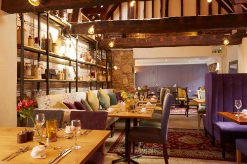 un restaurante con mesas de madera y sillas moradas en White Hart Hotel, en Dorchester on thames