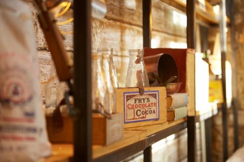 a shelf with jars and a box on it at White Hart Hotel in Dorchester on Thames