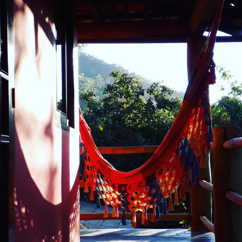 a red hammock in a room with a view at Mandacaru Chalés e Suítes Itamambuca in Ubatuba