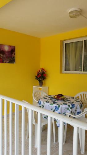 a dining room with a white table and a yellow wall at Location tropical in Sainte-Anne