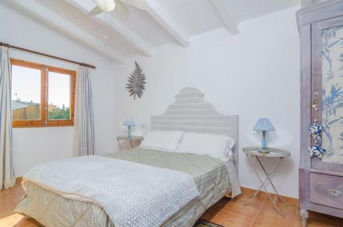 a white bedroom with a bed and a window at Can Rius in Muro