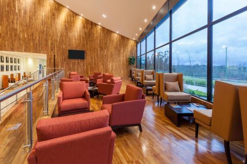 a waiting room with chairs and tables and windows at Wyndham Quito Airport in Tababela