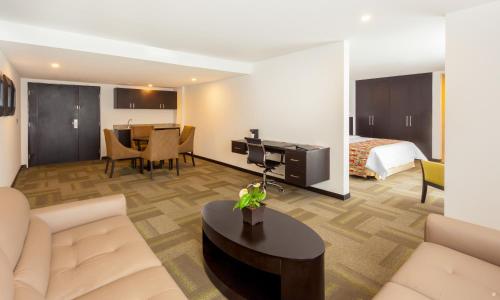a hotel room with a bed and a living room at Wyndham Quito Airport in Tababela