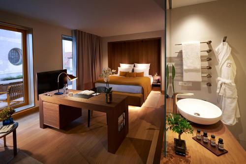 a hotel room with a bed and a desk and a bathroom at BEYOND by Geisel - Adults only in Munich
