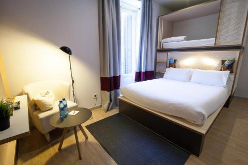 Habitación de hotel con cama, silla y mesa en Toc Hostel Madrid, en Madrid