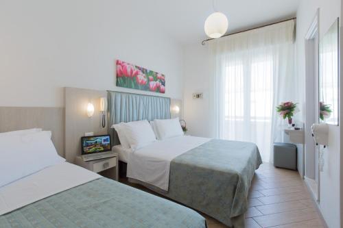 una camera d'albergo con due letti e una televisione di Hotel La Capinera a Bellaria-Igea Marina