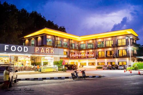 un parque de comida con dos motocicletas estacionadas frente a un edificio en The Lephant Hotel en Surat Thani