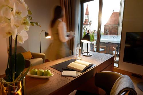 eine Frau steht in einem Wohnzimmer mit einem Tisch mit einer Lampe in der Unterkunft BEYOND by Geisel in München