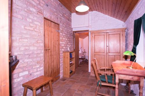 Cette chambre dispose d'une table, de chaises et d'un mur en briques. dans l'établissement Railway Crossing Cottage, à Murlas Bridge