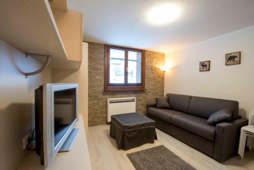 a living room with a couch and a flat screen tv at Casa Penia 2 in Canazei