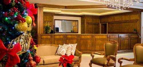 a room with a christmas tree and a couch and chairs at Sky Serra Hotel in Gramado