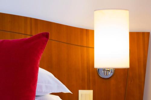 uma almofada vermelha sentada numa cama com um candeeiro em Europe Hotel Paris Eiffel em Paris