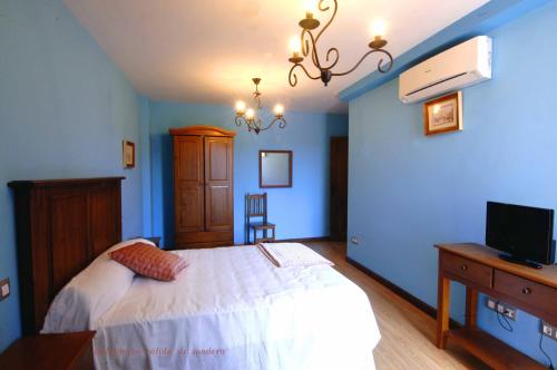 um quarto com uma cama branca e uma televisão em Apartamentos Sierra de Francia em Monsagro