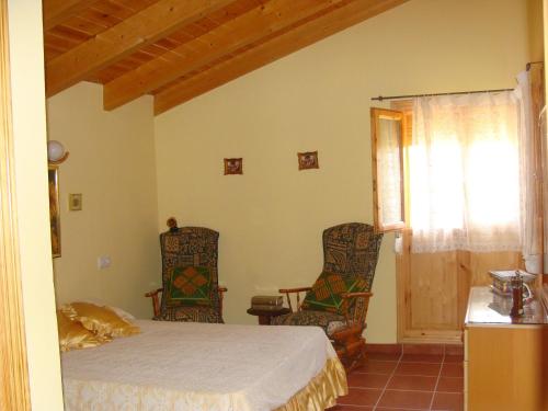 a bedroom with a bed and two chairs at Casa Los Lagos in Alcalá de la Selva