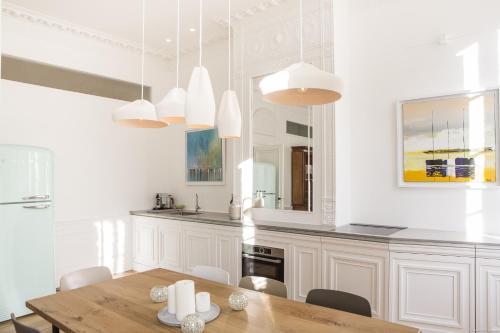 a kitchen with a wooden table and white cabinets at Intendance beautiful apartment in Bordeaux