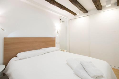 サン・セバスティアンにあるLUXURY IN OLD TOWN NEAR BEACH - by www,SanSebastianApartments,esの白いベッド1台(木製ヘッドボード付)が備わるベッドルーム1室が備わります。