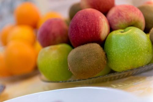 a bowl of apples and kiwis on a table with oranges at Colina do Mar in Albufeira