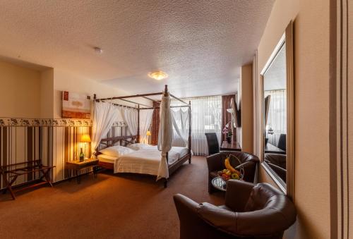 a bedroom with a canopy bed and two chairs at City Hotel Stolberg in Stolberg