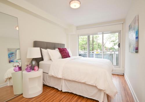 ein weißes Schlafzimmer mit einem großen Bett und einem Fenster in der Unterkunft LIV Extended Stay in Ottawa