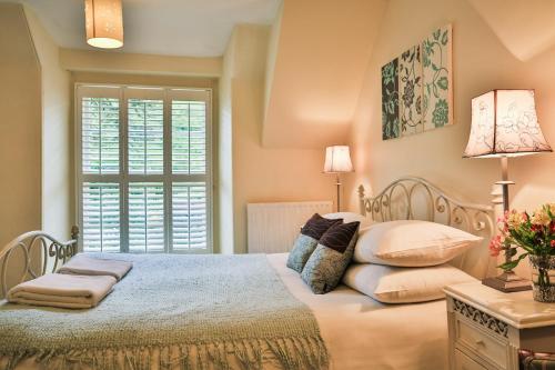 sypialnia z łóżkiem z poduszkami i oknem w obiekcie Combe House Hotel w mieście Holford
