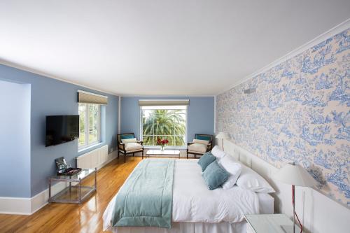 a bedroom with blue walls and a bed and a tv at Hotel Isla Seca in Zapallar