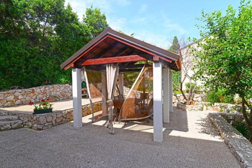 a gazebo with a swing in a yard at Apartments Ana in Mali Lošinj