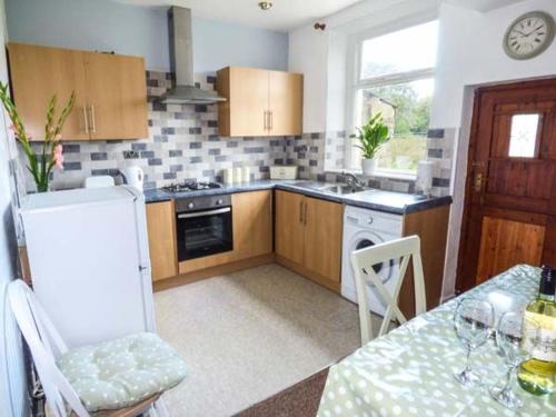 a kitchen with wooden cabinets and a table with chairs at Fell Cottage in Keighley