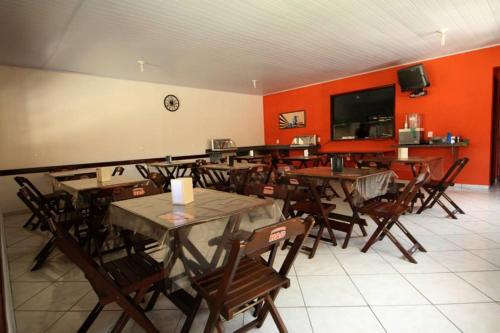 a dining room with tables and chairs and red walls at Pousada H&D in Angra dos Reis