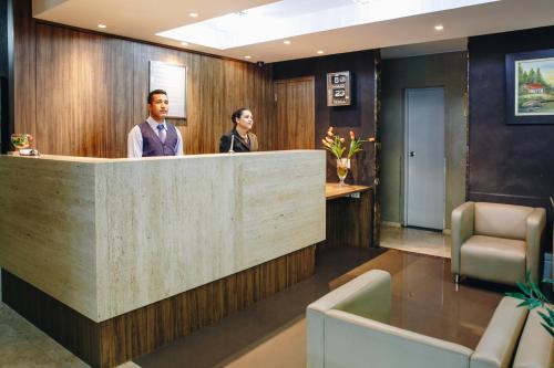 two people standing at the reception desk of a salon at Athus Brasilia Hotel by Bsb Inn in Brasilia