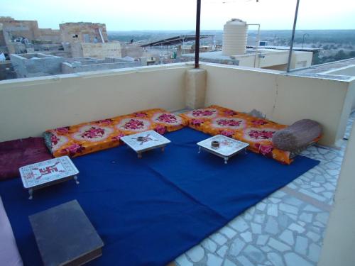 a table on a balcony with a blue blanket and tables at Ganesh Guest House in Jaisalmer