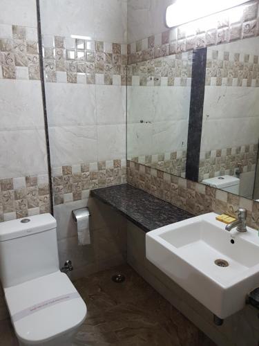 a bathroom with a white toilet and a sink at Swagath Grand Suchitra in Hyderabad