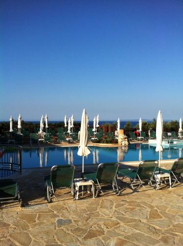 un gruppo di sedie e ombrelloni accanto alla piscina di Ariadne Apartments a Tsilivi