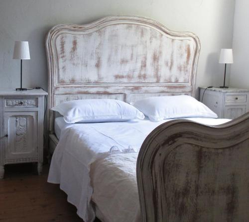 a white bed with a large headboard and two night stands at les Didascalies in Vic-Fezensac