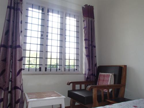 a room with a chair and a window at Coorg 4 C's Little Paradise in Madikeri