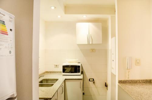 a small kitchen with a microwave and a sink at Lofty Departamentos Temporarios in Cordoba