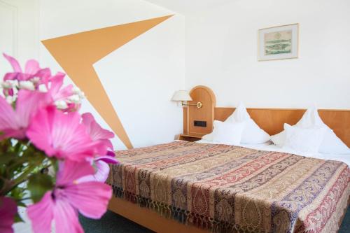 a hotel room with a bed with pink flowers at Insel-Hof Reichenau Hotel-garni in Reichenau