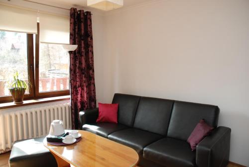 a living room with a black couch and a table at Willa Gościnny Próg in Krościenko