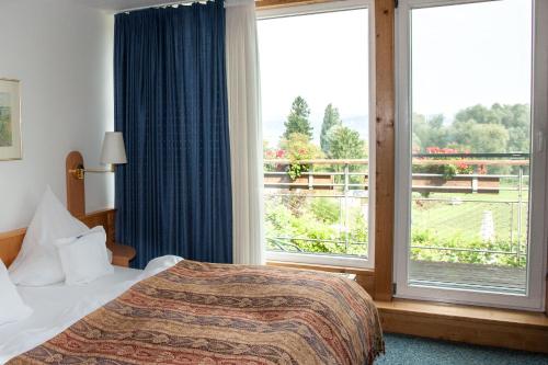 a hotel room with a bed and a large window at Insel-Hof Reichenau Hotel-garni in Reichenau