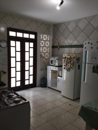 a kitchen with white appliances and a large window at Linda casa na Praia do Flamengo in Salvador