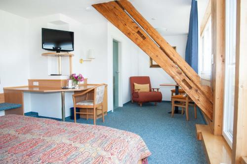 a hotel room with a bed and a desk and a table at Insel-Hof Reichenau Hotel-garni in Reichenau