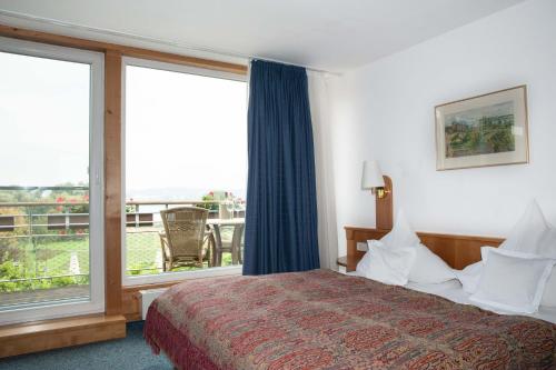 a hotel room with a bed and a large window at Insel-Hof Reichenau Hotel-garni in Reichenau
