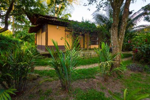 a small yellow house in the middle of a garden at Paraty Villa d`agua Temporada in Paraty